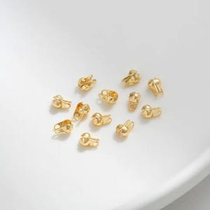 May include: A close-up of a group of gold-toned metal clasps, perfect for jewelry making or crafting projects.