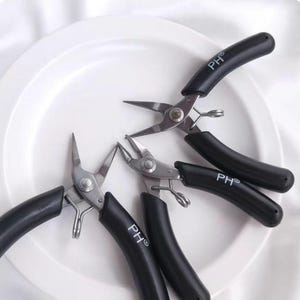 May include: Three black handled pliers with silver metal jaws. The pliers are labeled "PH®" on the handles.