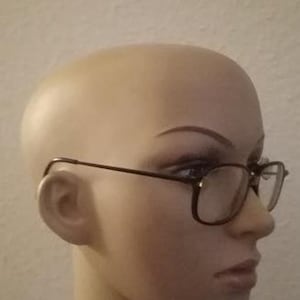 Op de afbeelding: Een mannequin met een zwarte bril met een bruin plastic montuur.