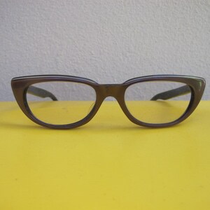 Könnte beinhalten: Eine braune Cat-Eye-Brille mit einem dünnen schwarzen Rahmen.