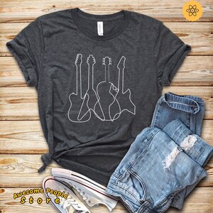 May include: A dark gray t-shirt with a white outline of four guitars. The guitars are drawn in a continuous line.