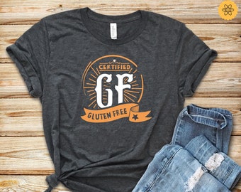 Puede incluir: Una camiseta gris oscuro con un gráfico de un círculo con el texto "CERTIFIED GF GLUTEN FREE" en naranja y blanco.
