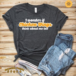 May include: A dark grey t-shirt with the text "I wonder if Chicken Wings think about me too" in white with the word "Chicken Wings" in orange.