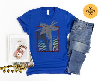 May include: A royal blue t-shirt featuring a graphic of a palm tree within a red and white frame. The palm tree is grey and has a rainbow-coloured background.