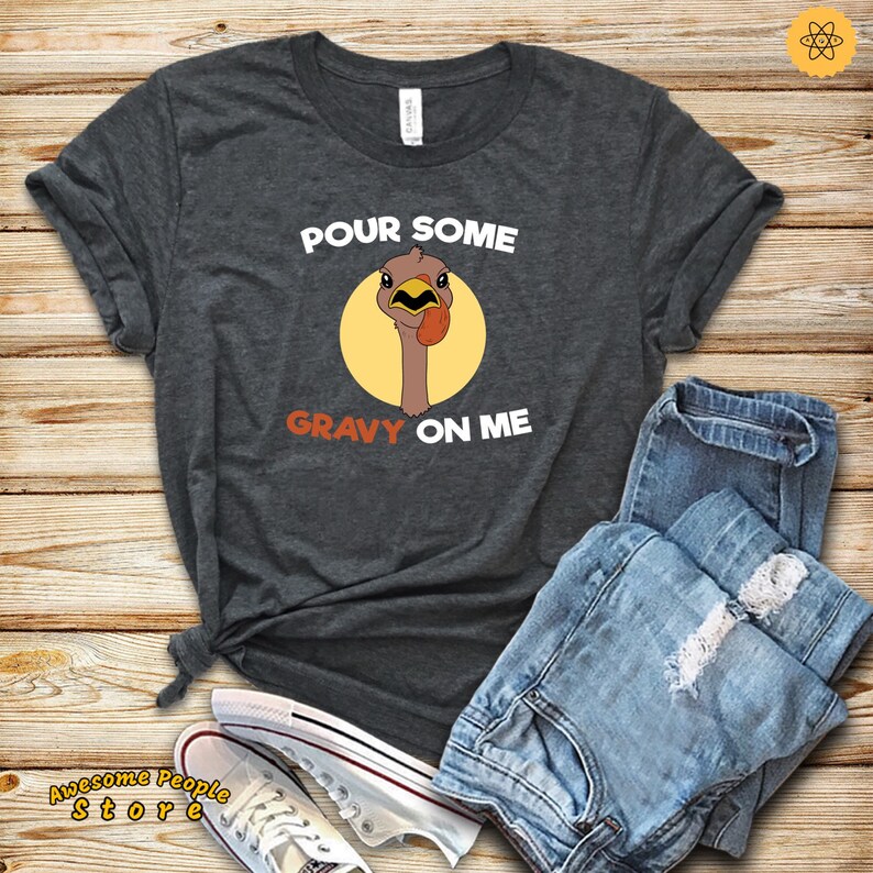 May include: A dark gray t-shirt with the text "POUR SOME GRAVY ON ME" and a cartoon turkey with a red wattle and yellow eyes.
