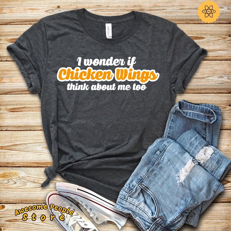 May include: A dark grey t-shirt with the text "I wonder if Chicken Wings think about me too" in white with the word "Chicken Wings" in orange.