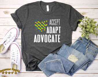 May include: A gray t-shirt with a white heart made of puzzle pieces and the text "ACCEPT ADAPT ADVOCATE".