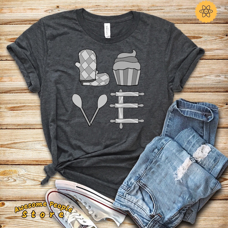 Może przedstawiać: Szary t-shirt z napisem "LOVE" napisanym za pomocą ikon związanych z pieczeniem. Litera "L" to szary rękawica do piekarnika, "O" to szary cupcake, "V" to dwie szare łyżki do mieszania, a "E" to trzy szare wałki do ciasta.