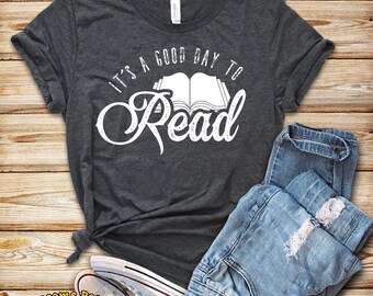 May include: A dark gray t-shirt with the text "It's a good day to read" in white. The text is stylized with a book graphic and a vintage font.