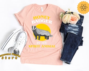 May include: A pink t-shirt with the text "Honey Badger is my spirit animal" in yellow and white lettering. A cartoon honey badger is illustrated in the center of the shirt.