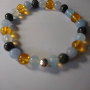 May include: A bracelet made of blue, yellow, and gray beads with a silver charm.