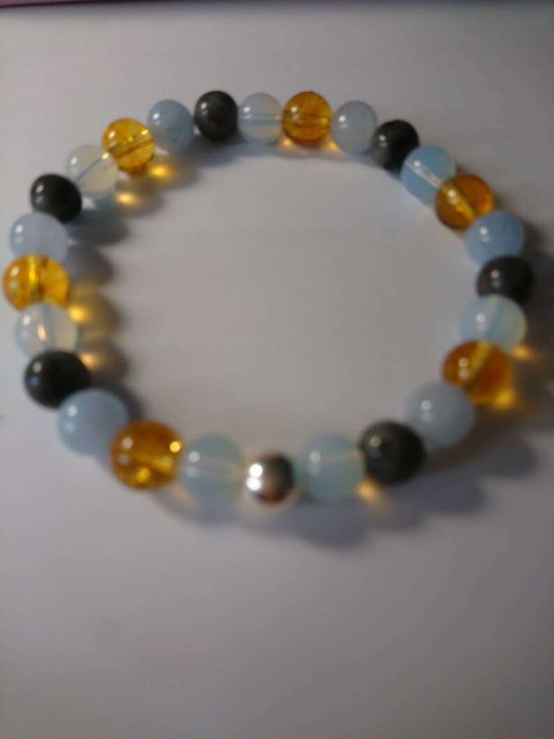 May include: A bracelet made of blue, yellow, and gray beads with a silver charm.