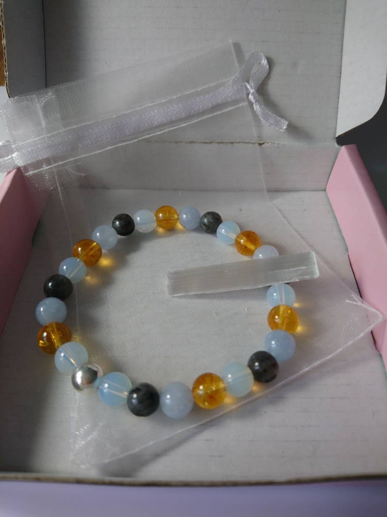 May include: A bracelet made of blue, orange, and gray beads in a clear organza bag. The bracelet is in a pink and white gift box.