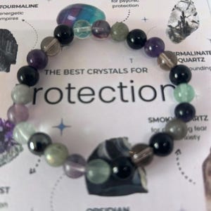 May include: A bracelet made of various crystals, including amethyst, fluorite, smoky quartz, and obsidian. The bracelet is on a white background with text that reads "The Best Crystals for Protection".