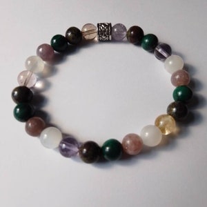 May include: A bracelet made of various semi-precious stones, including green, brown, pink, purple, and white beads. The bracelet has a silver charm in the center.