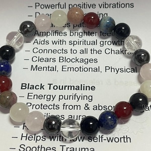 Könnte beinhalten: Ein schwarzes Turmalin-Armband mit verschiedenen farbigen Edelsteinen, darunter klarer Quarz, Rosenquarz und Hämatit. Das Armband wird mit einer Beschreibung der heilenden Eigenschaften von schwarzem Turmalin geliefert, darunter Energiereinigung, Schutz und Erdung.