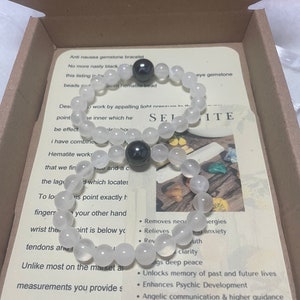 Pu&ograve; includere: Un braccialetto di selenite bianca con due perle di ematite nere. Il braccialetto &egrave; in una scatola con una descrizione dei benefici della selenite e dell'ematite. Il testo recita: "Braccialetto di pietra di selenite antinausea. Niente pi&ugrave; nero sgradevole. Questo elenco &egrave; per una perla di ematite da 8 mm.  ...  Elimina le energie negative. Allevia lo stress e l'ansia.  ...  Sblocca la memoria di vite passate e future. Migliora lo sviluppo psichico. Comunicazione angelica e guida superiore. Incoraggia la consapevolezza di s&eacute;."