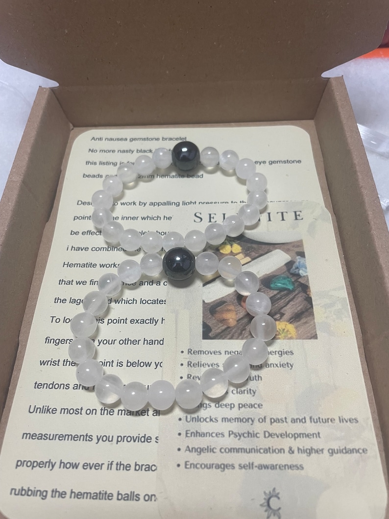 Pu&ograve; includere: Un braccialetto di selenite bianca con due perle di ematite nere. Il braccialetto &egrave; in una scatola con una descrizione dei benefici della selenite e dell'ematite. Il testo recita: "Braccialetto di pietra di selenite antinausea. Niente pi&ugrave; nero sgradevole. Questo elenco &egrave; per una perla di ematite da 8 mm.  ...  Elimina le energie negative. Allevia lo stress e l'ansia.  ...  Sblocca la memoria di vite passate e future. Migliora lo sviluppo psichico. Comunicazione angelica e guida superiore. Incoraggia la consapevolezza di s&eacute;."