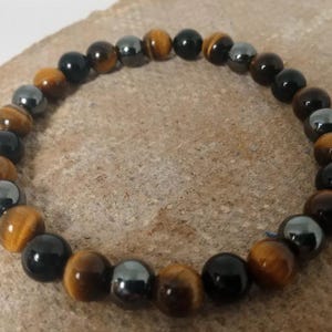 May include: A beaded bracelet with alternating black, brown, and silver beads.