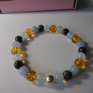 May include: A bracelet made of blue, yellow, and black beads with a silver bead in the center.