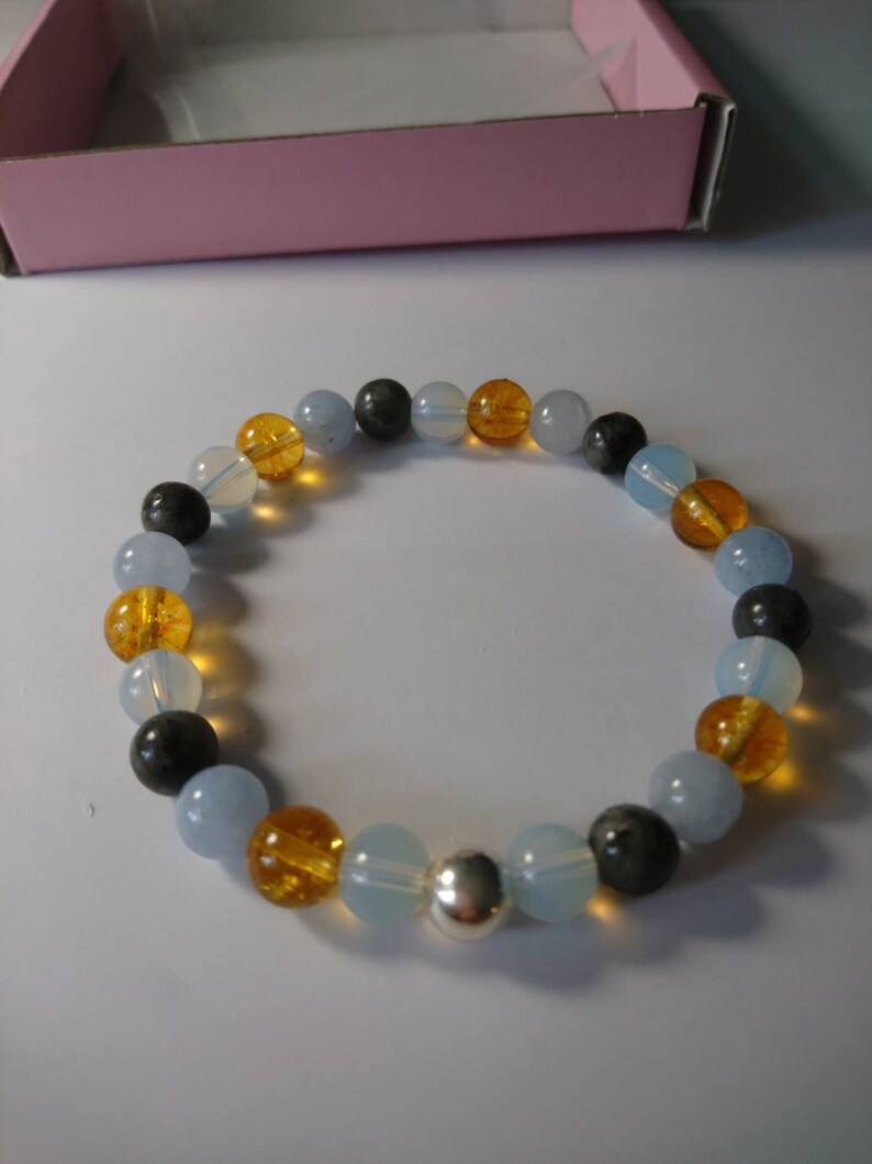 May include: A bracelet made of blue, yellow, and black beads with a silver bead in the center.