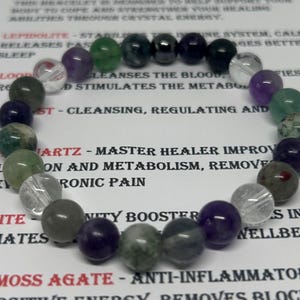 Puede incluir: Una pulsera de cuentas con una variedad de piedras preciosas de colores, incluyendo cuentas verdes, moradas y transparentes. La pulsera se muestra sobre una superficie blanca con texto que describe las propiedades de cada piedra. Es una joya.