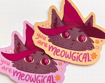 May include: Two pink and orange stickers with a cartoon cat wearing a pink witch hat. The cat has large, pink eyes and a surprised expression. The text on the stickers reads "you are meowgical".