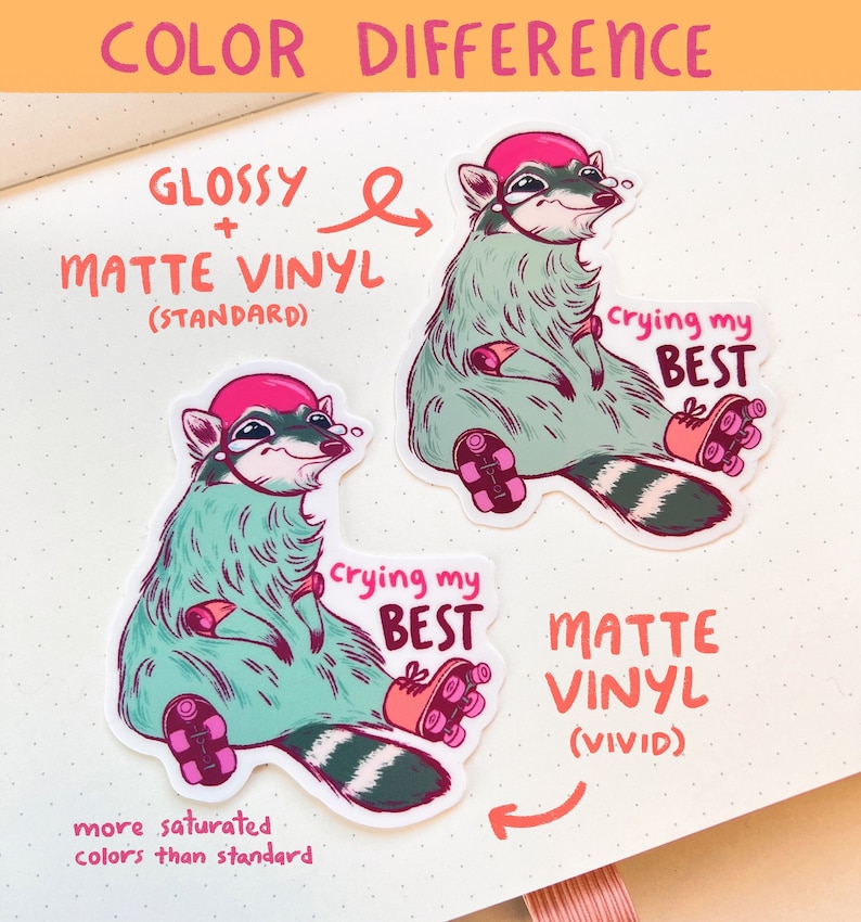 May include: Two raccoon stickers, one with a glossy finish and one with a matte finish. Both stickers feature a raccoon wearing a pink helmet and roller skates, with the text "crying my best". The glossy sticker has more saturated colors than the matte sticker.