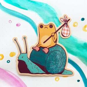 May include: A yellow frog with a red and white checkered bag sits on a green snail with a brown shell. The frog is holding a stick with a red and white checkered bag attached to the end.