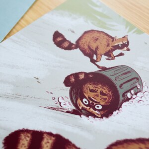 May include: A whimsical illustration of three raccoons, one of which is upside down in a green bin. The raccoons are drawn in a cartoon style with brown fur and black eyes. The background is a light grey with a subtle texture.