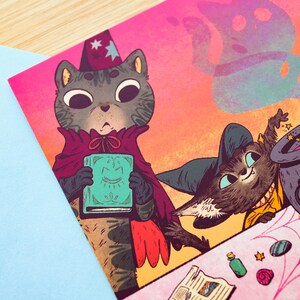 May include: Two cats dressed as witches are making a potion in a cauldron. One cat is holding a book with a smiling face on the cover. The other cat is stirring the cauldron with a wand. The cauldron is filled with pink liquid and there are stars and smoke coming out of it.