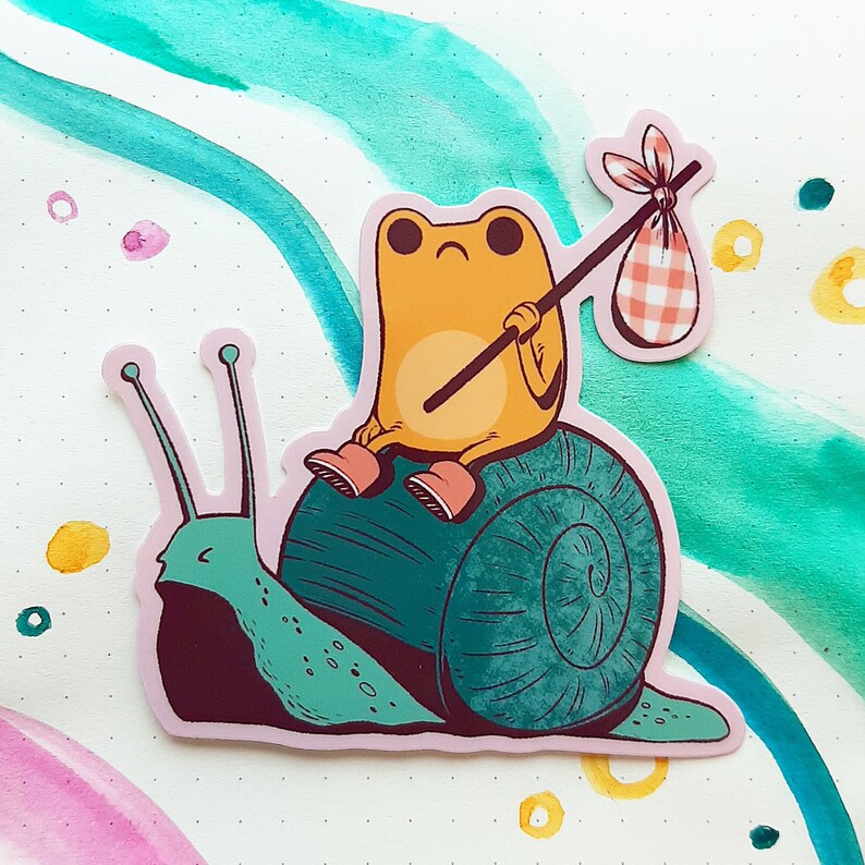 May include: A green snail with a yellow frog on its back. The frog is holding a red and white checkered bag and a stick. The snail is on a white background with blue and green watercolor washes.
