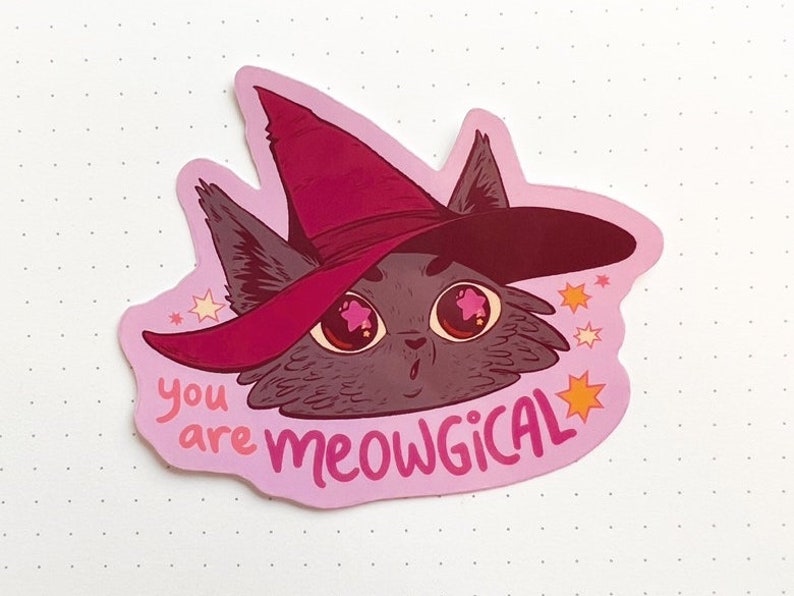 May include: A pink sticker featuring a cartoon illustration of a black cat wearing a pink witch hat with stars. The text "you are meowgical" is written below the cat.