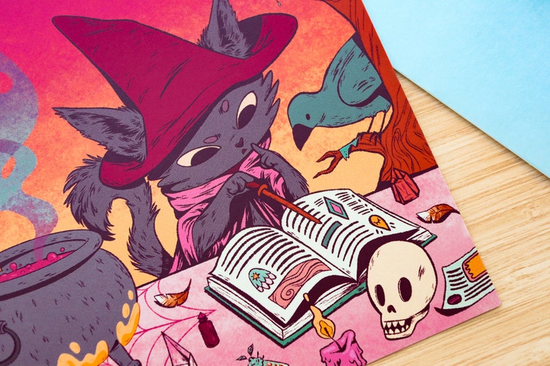 May include: A black cat wearing a pink and red witch's hat and robe is reading a book with a wand in its paw. A blue bird is perched on a branch in the background. There is a cauldron with a purple liquid, a skull, and other magical items on the table.