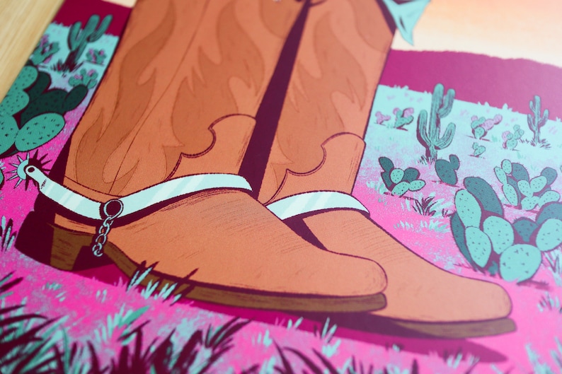 May include: A pair of brown leather cowboy boots with silver spurs and white accents. The boots are set against a pink and green desert landscape with cactus plants.