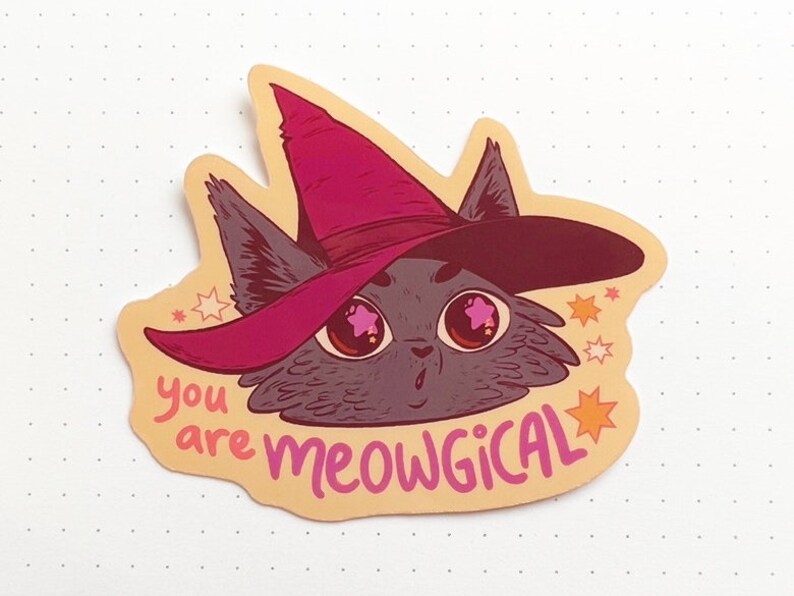 May include: A sticker featuring a cartoon cat wearing a pink witch hat with stars around it. The text "you are meowgical" is written below the cat.