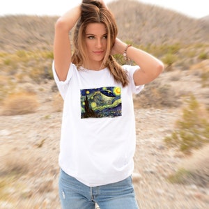 May include: White t-shirt with a graphic print of Vincent van Gogh's Starry Night with a UFO flying over the town.