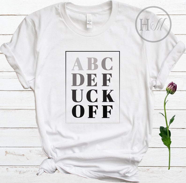 May include: White t-shirt with a black and gray graphic that says "ABC DEF UCK OFF" in a blocky font.