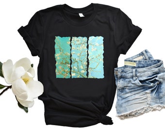 May include: Black t-shirt with a graphic print of a painting of a tree with white blossoms. The painting is in a teal blue color.