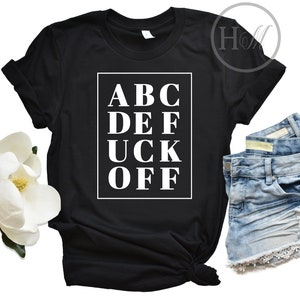 May include: Black t-shirt with white text that reads "ABC DEF UCK OFF" in a box.