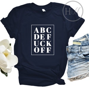 May include: A navy blue t-shirt with a white graphic that says "ABC DEF UCK OFF" in a box.