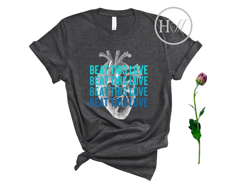 May include: A dark gray t-shirt with a graphic of a human heart and the text "Beat This Love" repeated four times in blue and teal.