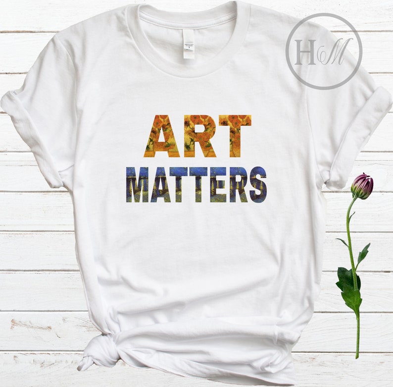May include: White t-shirt with the text "ART MATTERS" in a stylized font. The letters are filled with a painting of sunflowers and a starry night.