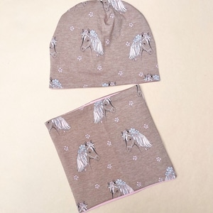 May include: A brown knitted hat and matching neck warmer with a white horse print and small pink flowers.