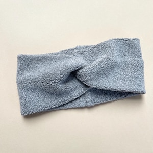 Puede incluir: Una diadema de pelo azul claro y peluda con un diseño de nudo retorcido.