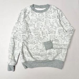 Puede incluir: Una sudadera gris con fondo blanco y un patrón de coches y camiones negros.