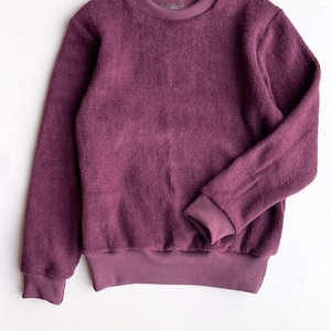 Puede incluir: Una sudadera de color morado peluda con cuello y puños de canalé.