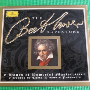 May include: A gold and black box with the text "THE Beethoven ADVENTURE" and a portrait of Beethoven. The box says "6 Hours of Powerful Masterpieces" and "6 Heures de Chefs-D'oeuvre Puissants".