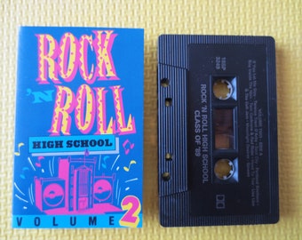 May include: A black cassette tape with the title "Rock 'n Roll High School Class of '89" and the text "Volume Two - Side A" printed on the label. The cassette tape is in a plastic case with a blue and pink cover that says "Rock 'n Roll High School Volume 2".
