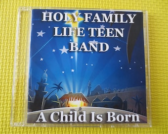 May include: A CD case with a blue background and stars. The text "HOLY FAMILY LIFE TEEN BAND" is in white letters. The text "A Child Is Born" is in white letters on a brown background.